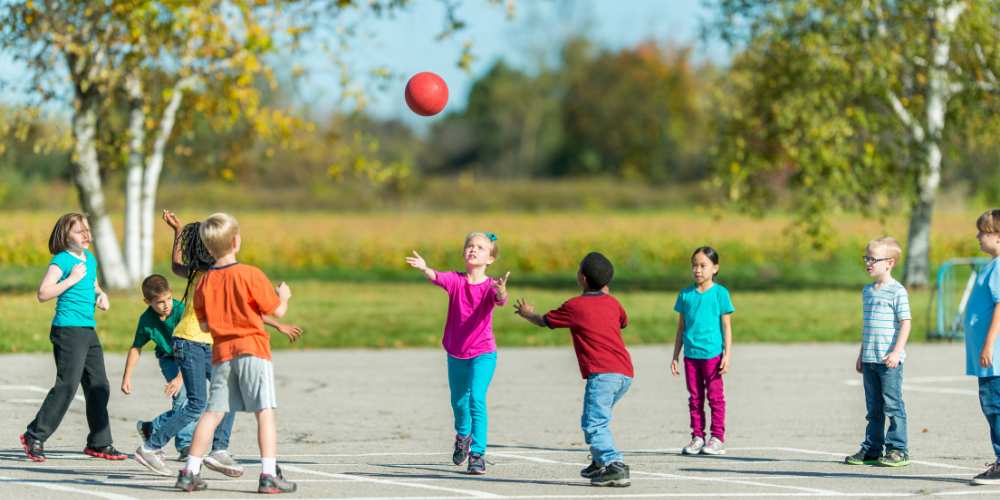 enfants jouant au ballon dans la cours d'école