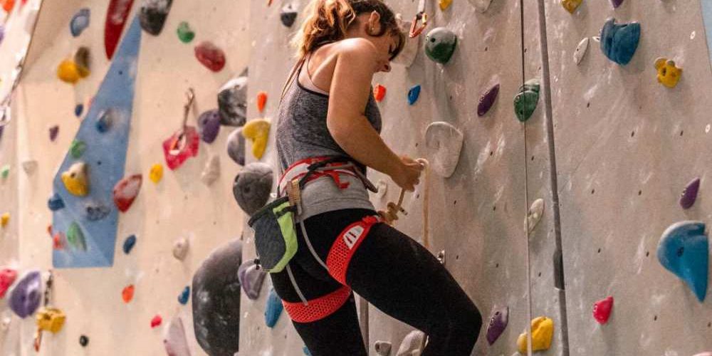 femme faisant de l'escalade sur un mure d'escalade en intérieur